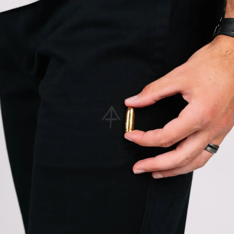 Brass bullet held by hand showcasing NEW Carrier Sweatpants Mk.II with patented retention waistband