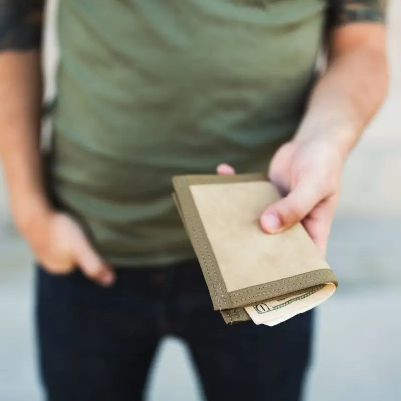 Brown leather wallet with money peeking out, featuring Coyote Combat Leather design