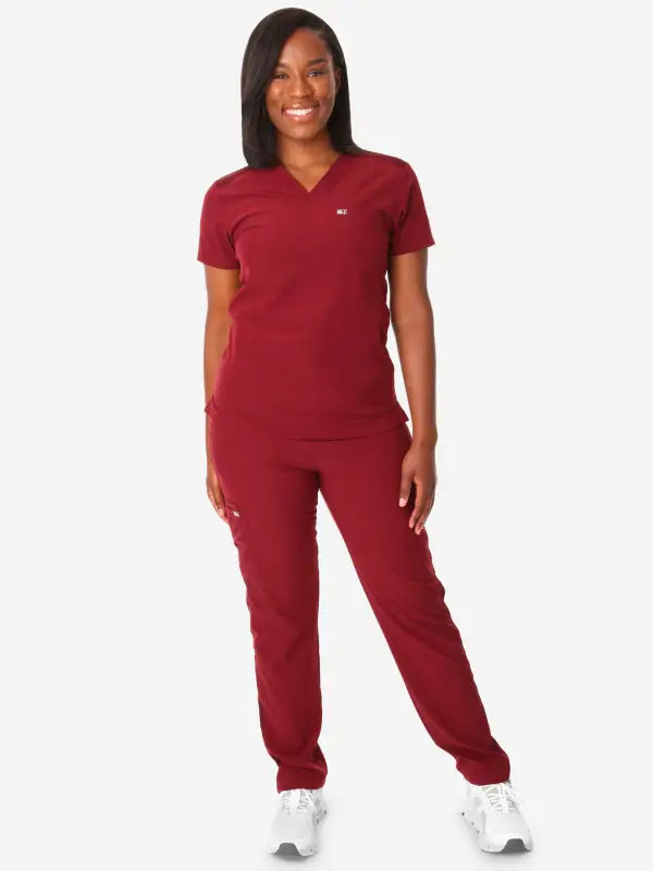 Burgundy women’s tuckable one-pocket scrub top with matching sweatpants and white sneakers