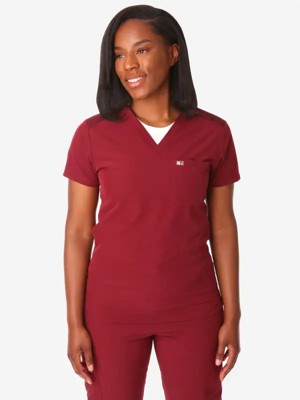 Burgundy women’s tuckable one-pocket scrub top with white undershirt neckline detail