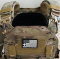 Camo tactical plate carrier with US flag patch, body armor, and medical kit for tactical readiness