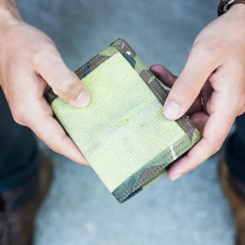 Camouflage-patterned Coyote Combat Leather wallet held open, showcasing its durability