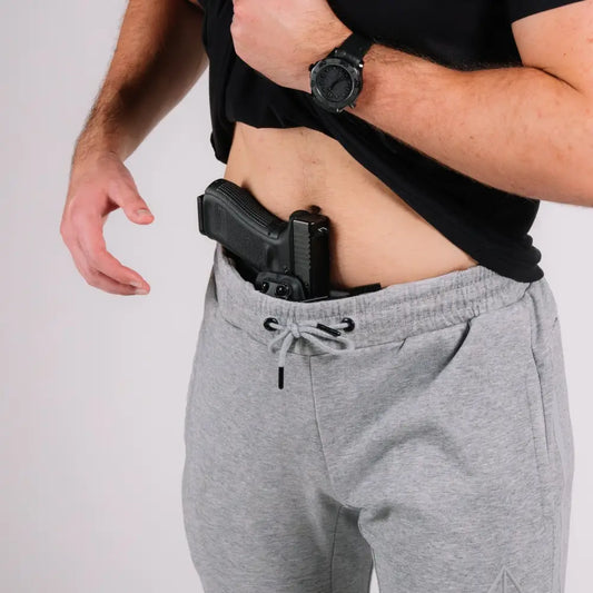 Black handgun in gray sweatpants with patented carrier retention waistband