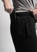 Hands adjusting a gray t-shirt to showcase Carrier Sweatpants featuring patented carrier retention