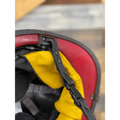 Close-up of a motorcycle helmet with red, yellow, and black panels featuring smooth leather chin straps