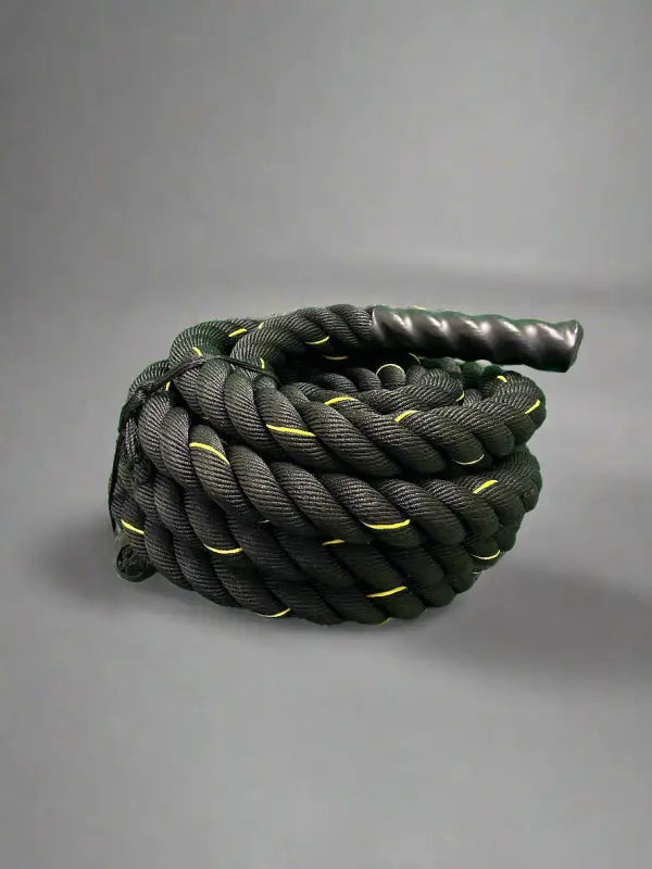 Coiled black firefighter battle rope with yellow accents and textured handle for first responders