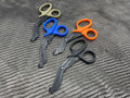 Four pairs of Compact Trauma Shears with colored handles arranged in a row