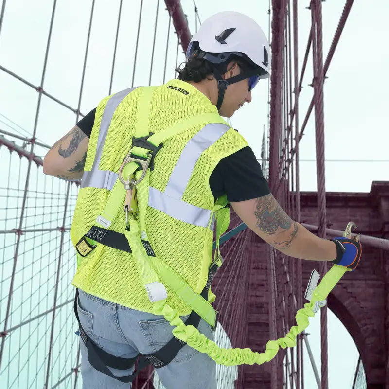 Construction worker in safety gear using a single leg internal shock-absorbing lanyard