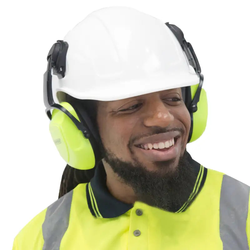 Smiling construction worker wearing slotted hard hats and 23dB NRR noise cancelling earmuffs