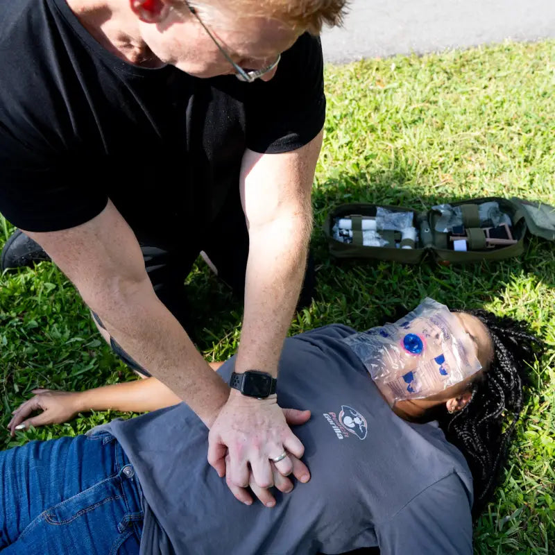 CPR training demonstration on grass with The First Responder IFAK Kit and firefighter swipe tool