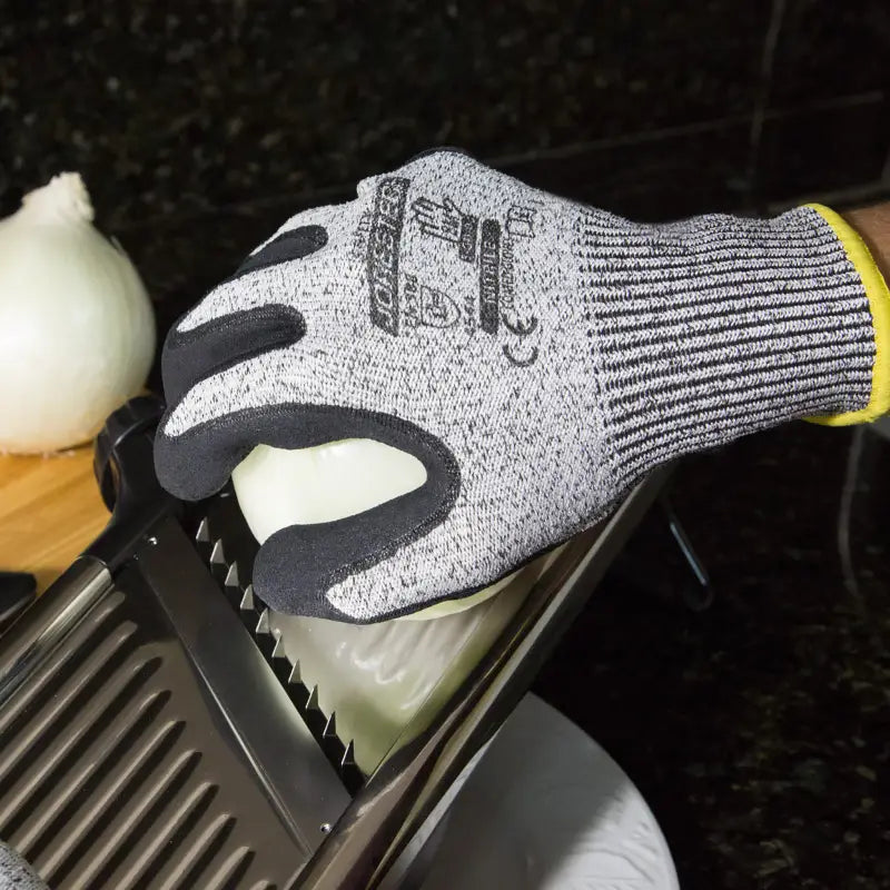 Cut-resistant safety work gloves with sandy nitrile dipped palms slicing an onion