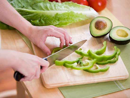 Person slicing green pepper with Finger Cut Kit for safe finger cut prevention