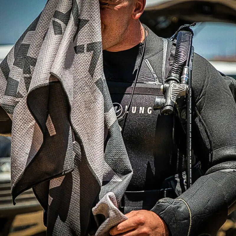 Diver in wetsuit with Tek Towel super absorbent fast-drying dive kit for remote dive sites