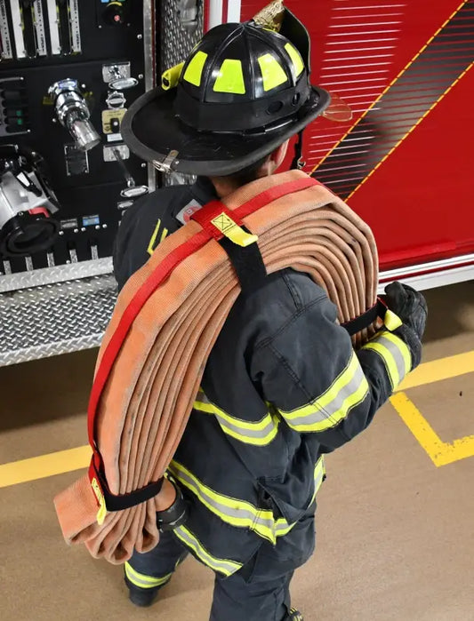 Firefighter carrying coiled fire hose with Adjustable Hose Bundle Strap Kit in Red