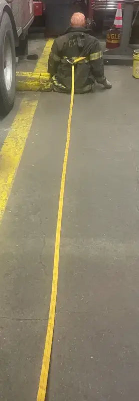 Firefighter in harness with long yellow strap for personal carry and fireground applications