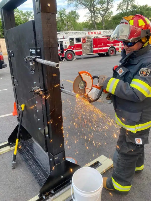 Firefighter cutting a metal door with a power saw on a Forcible Entry Door Prop