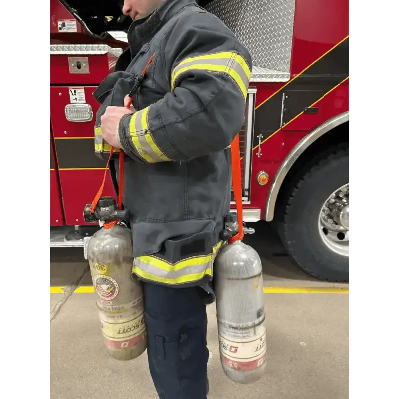 Firefighter in gear using SCBA Bottle Carrying Sling to transport SCBA bottles