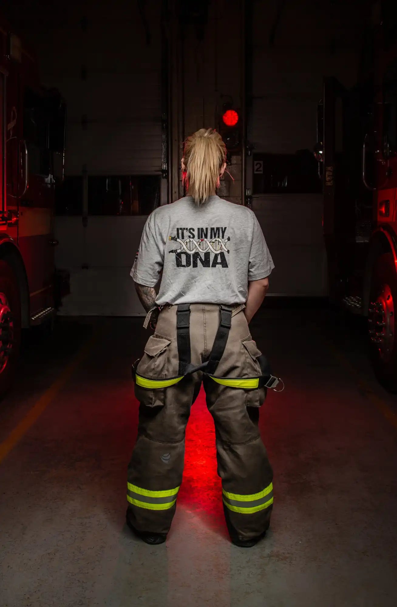 Firefighter wearing a shirt that says ’It’s in my DNA’ and standard protective gear.