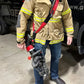 Firefighter in tan turnout gear with Genesis 11C extrication tool carrying strap