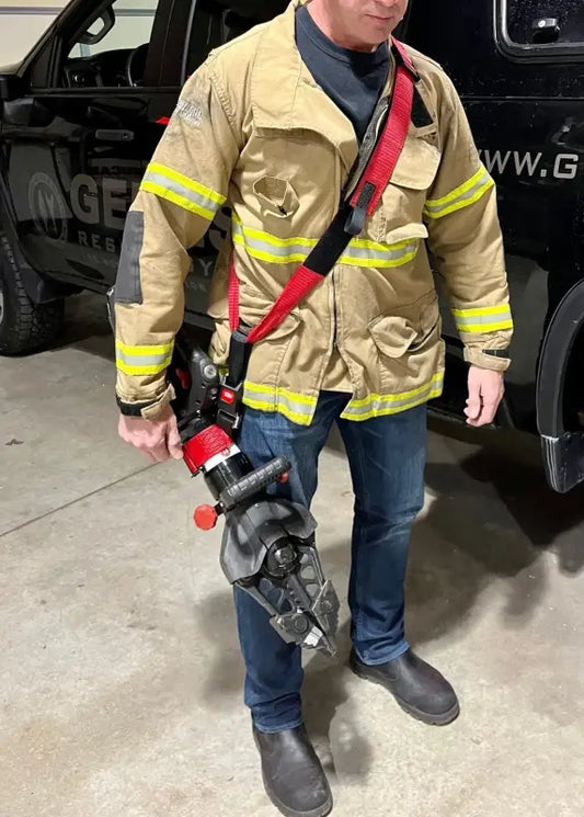 Firefighter in tan turnout gear with Genesis 11C extrication tool carrying strap