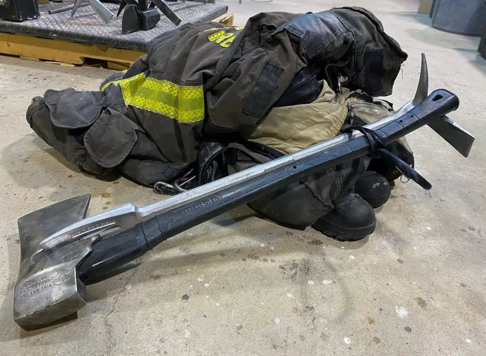 Firefighter’s Halligan tool beside turnout gear showcasing FMT Lanyard Strap and eye opening