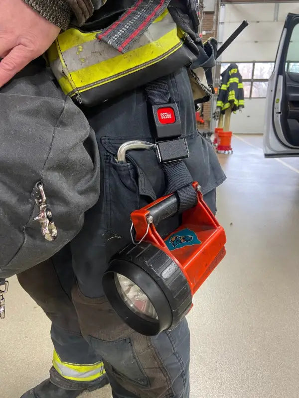 Firefighter’s handheld spotlight and Flashlight Strap-FFFS attached to gear