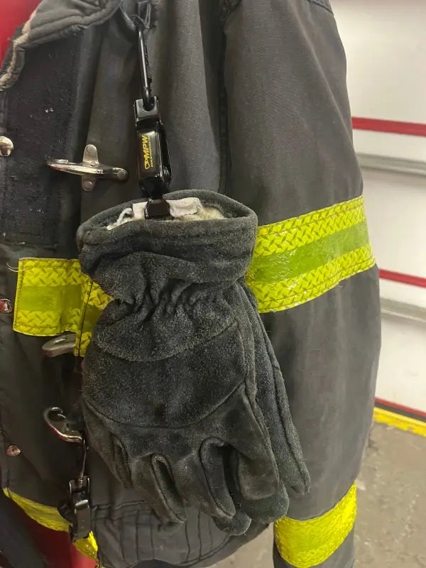 Firefighter’s protective glove hanging on turnout gear using Glove Clamp, a high-grade metal glove holder for first responders