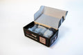 Black box with white lid showing FireWrap® HRD plastic film canisters, glow green kit sold