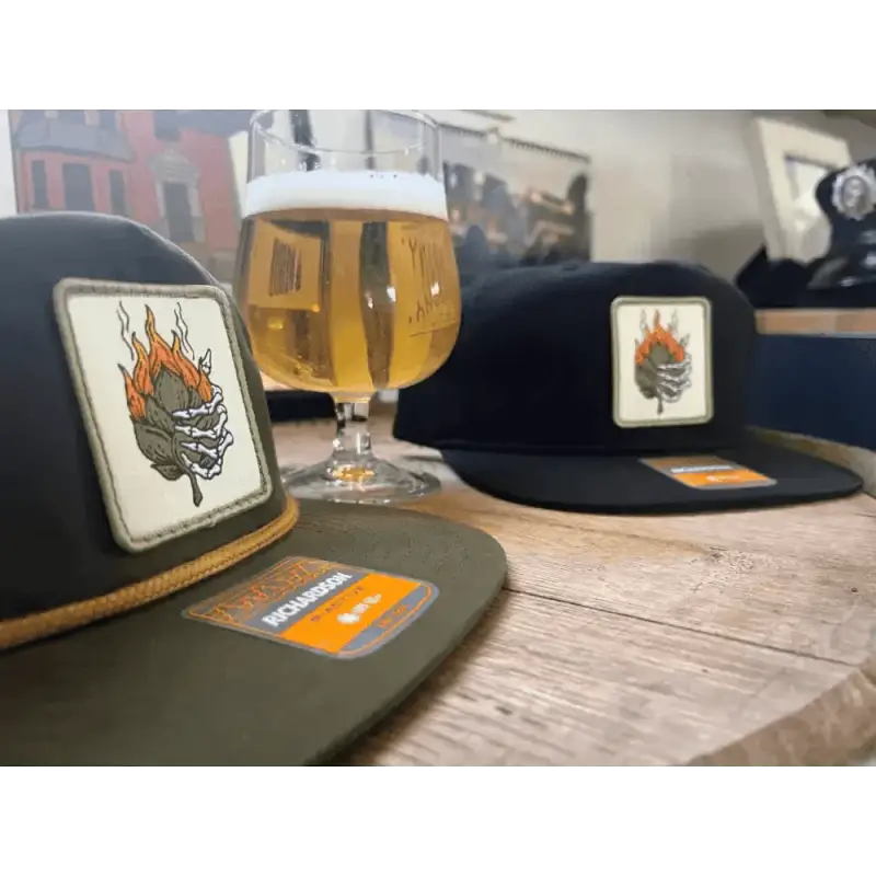 Glass of golden beer and Smokin Hop Brewery Hat with flaming logo patches