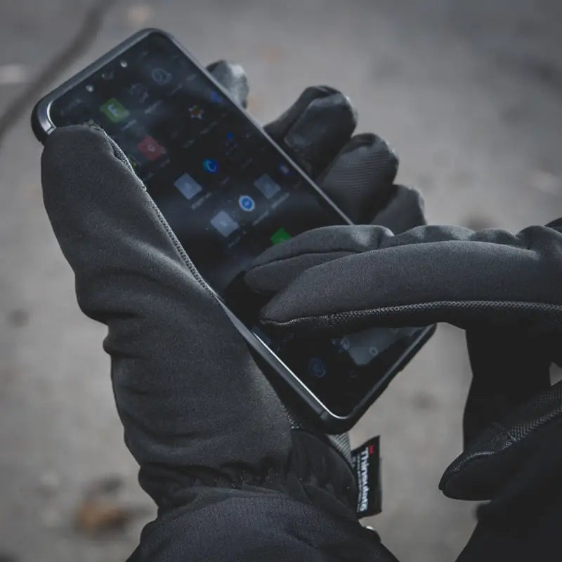 Gloved hands using a smartphone with M-Tac Gloves Soft Shell Thinsulate displayed