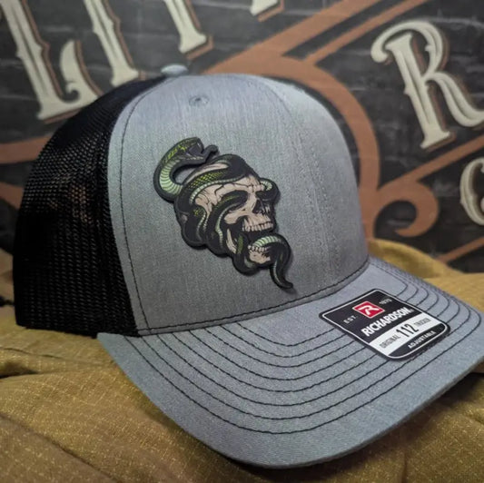 Gray and black trucker hat with serpent skull leather patch and skull leather patch