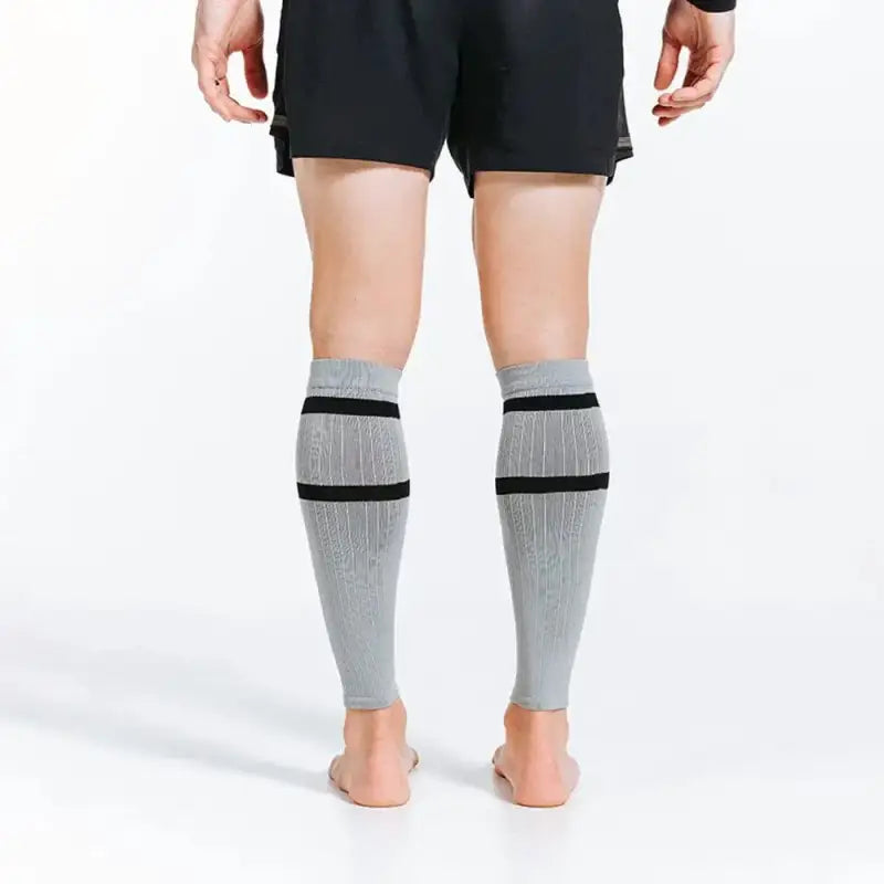 Gray compression calf sleeves with black stripes worn on calves for support and style