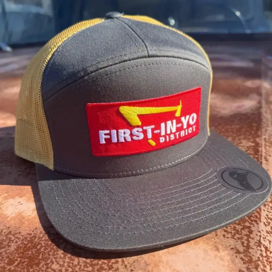 Gray and yellow mesh trucker hat with red First-In-Yo District patch for a stylish look