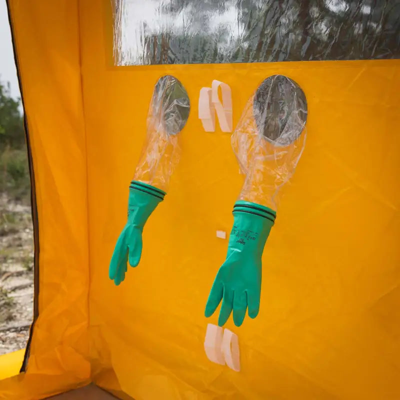 Green rubber gloves hanging upside down on orange surface for DS-1 Portable Decontamination Shower