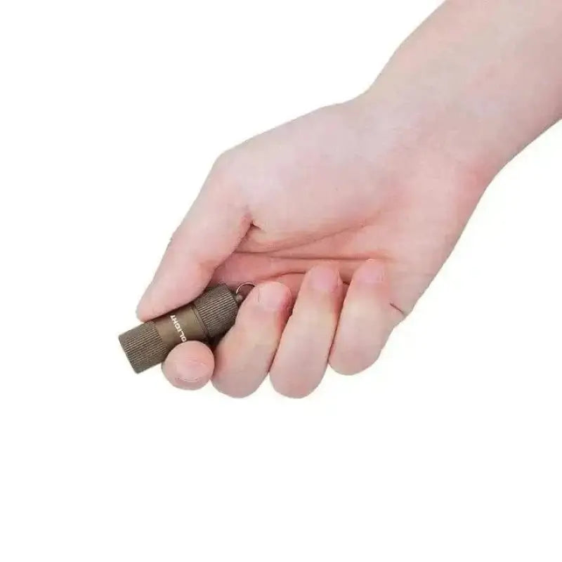 Hand holding a metallic hex key beside OLIGHT IR2 EOS Keychain Flashlight Kit - Desert Tan