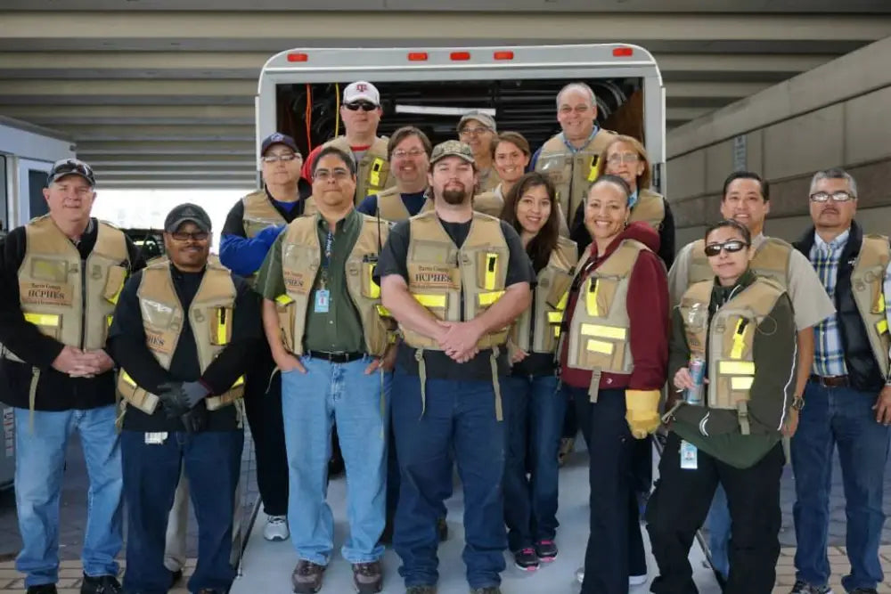 Group of workers in HCPHES Safety Vests gathered by a vehicle for safety briefing