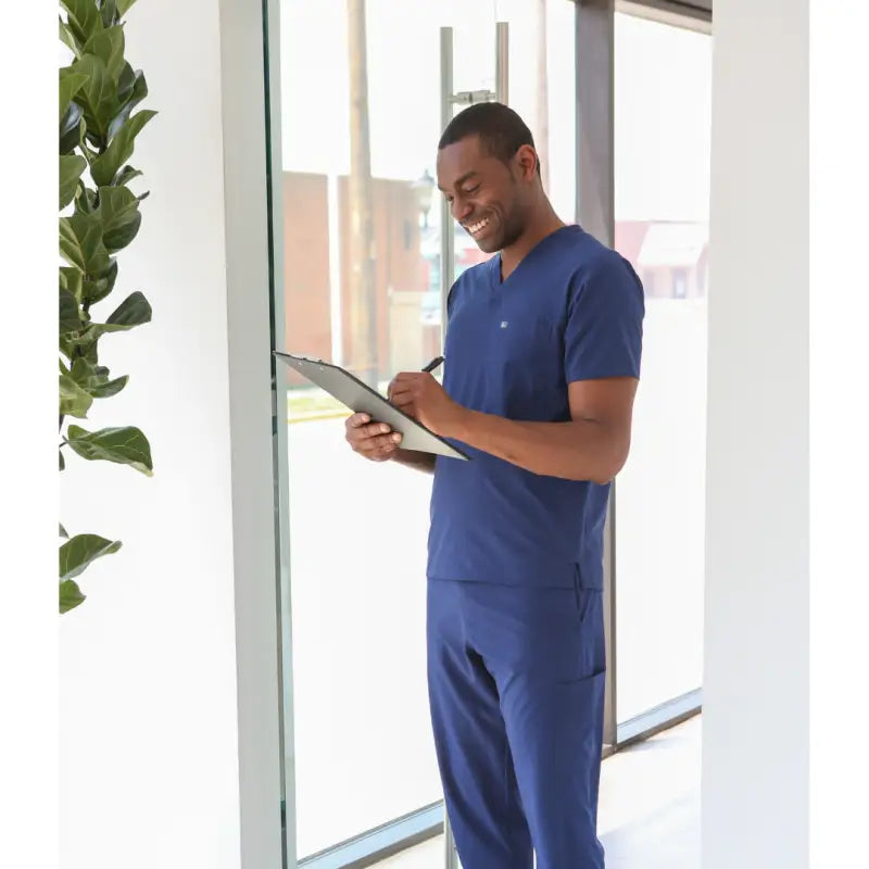 Healthcare worker in navy blue men’s double-pocket scrub top using a tablet device