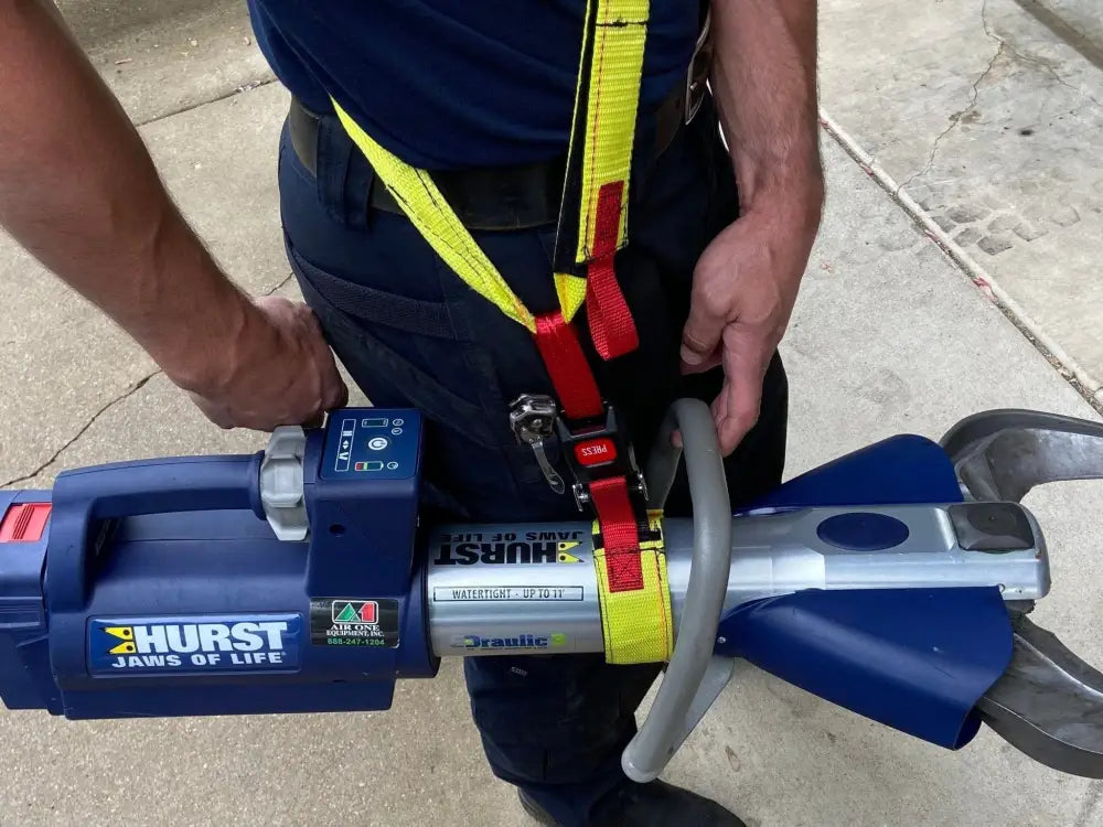 Hydraulic rescue tool Jaws of Life with blue and yellow components in Extrication Tool Carrying Strap