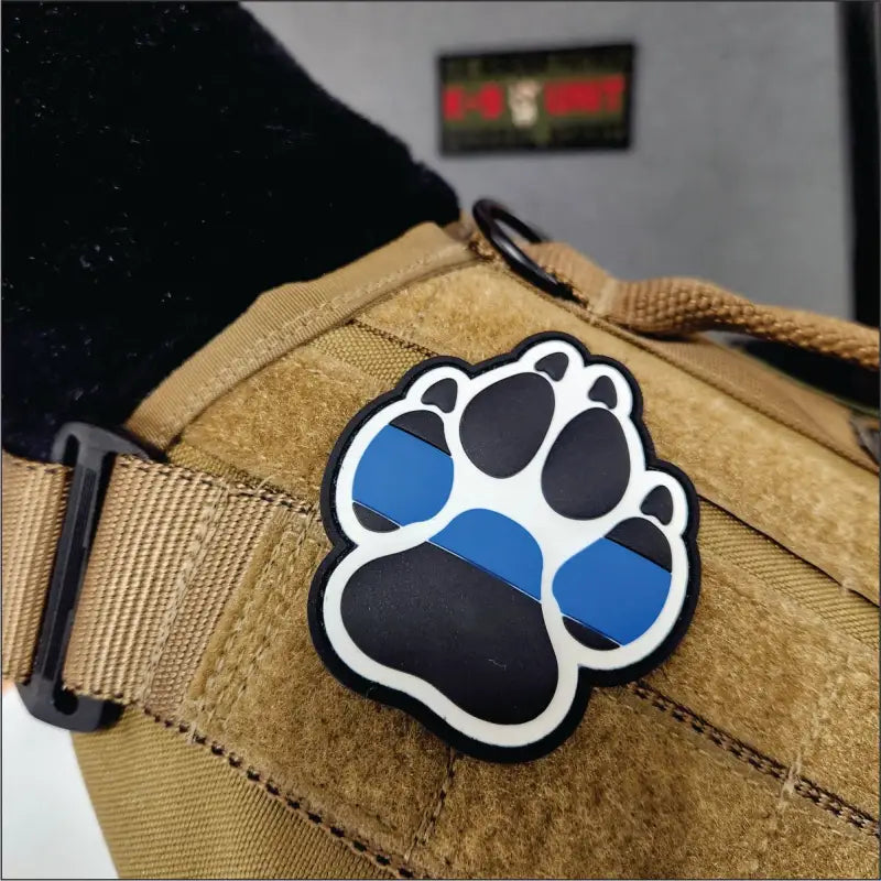 K-9 Thin Blue Line Dog Paw Print PVC Patch on tan tactical surface, 3 inch size