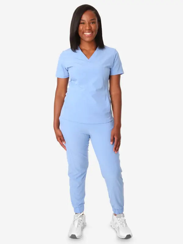 Light blue women’s stash-pocket scrub top paired with white sneakers for comfort and style