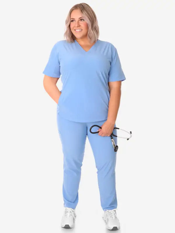 Light blue women’s stash-pocket scrub top paired with white sneakers for medical professionals