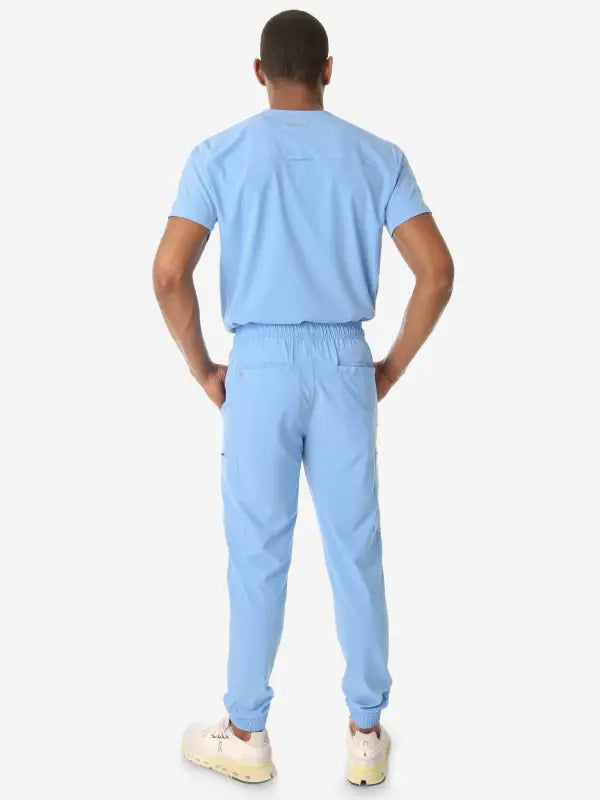 Light blue men’s double-pocket scrub top with matching sweatpants and white sneakers