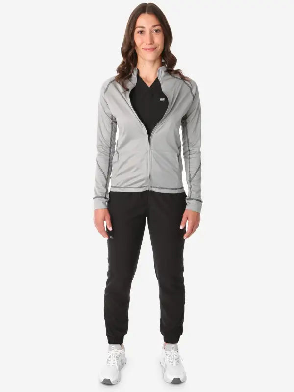 Light gray women’s scrub jacket with black pants and white sneakers outfit