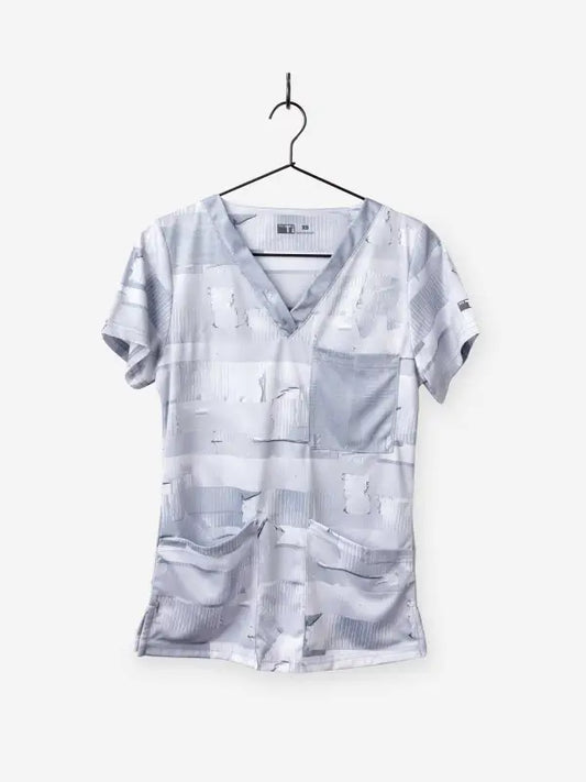 Light gray women’s duct tape scrub top with pockets hanging on a hanger