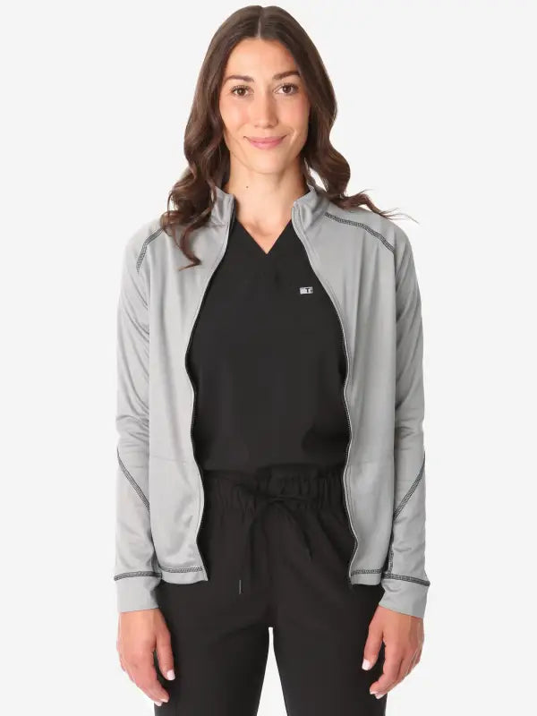 Light gray women’s scrub jacket stylishly layered over a black top for comfort