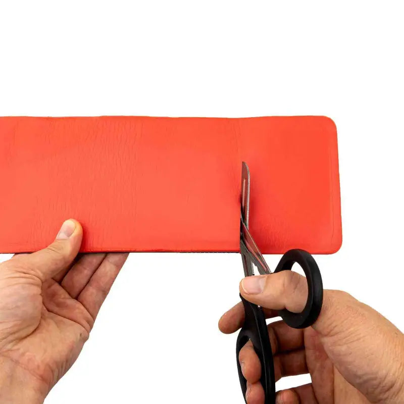 Hands using scissors to cut red paper for LINE2design Medical EMS Flex Roll Splint