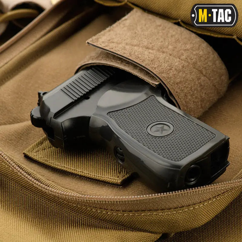 Black pistol in textured grip partially in M-Tac Concealed Carry Sling Bag Elite Gen.IV