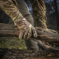 Camouflage-patterned M-Tac Gloves Fleece Thinsulate gripping a fallen tree branch