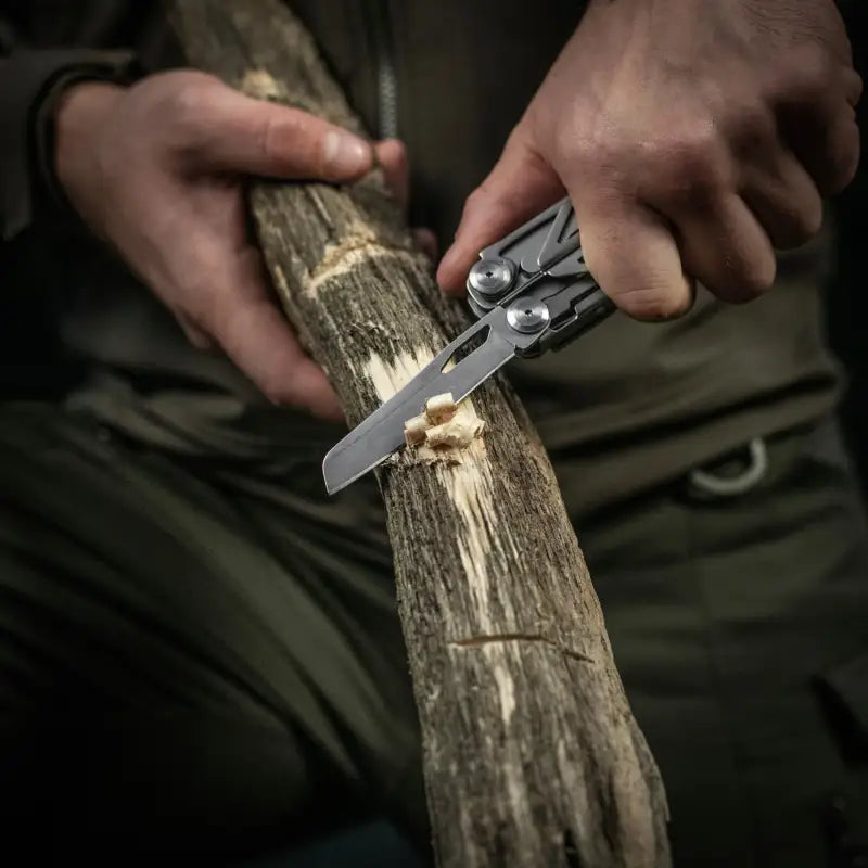 M-Tac Multitool Type 3 Grey in use carving a wooden stick with integrated pliers