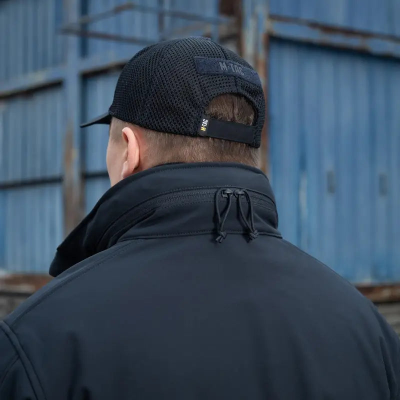 Back view of person in M-Tac Soft Shell Jacket with two shoulder pockets and black cap